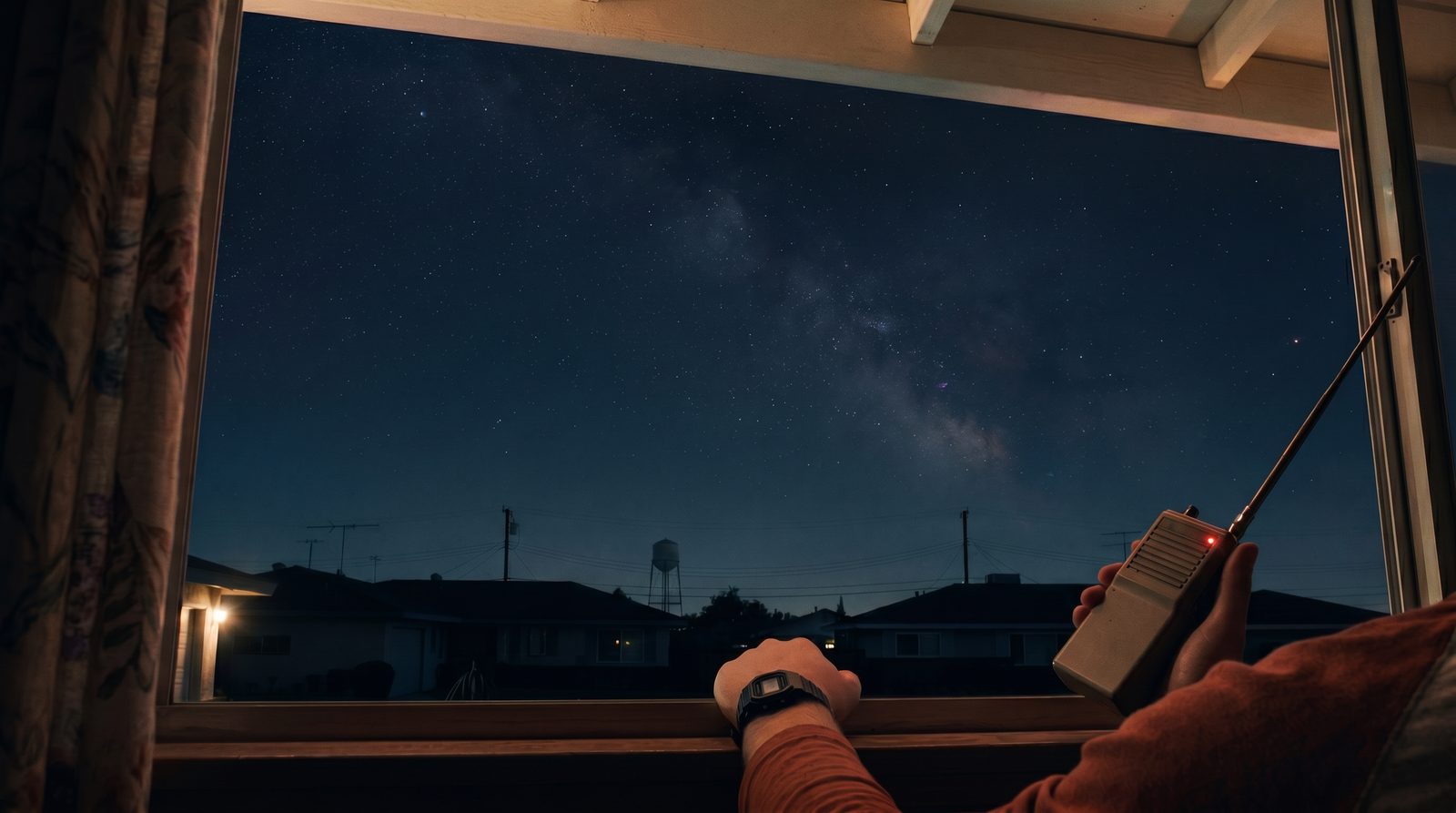 A hand holding a walkie-talkie at an open window, rooftops and a starred night sky beyond
